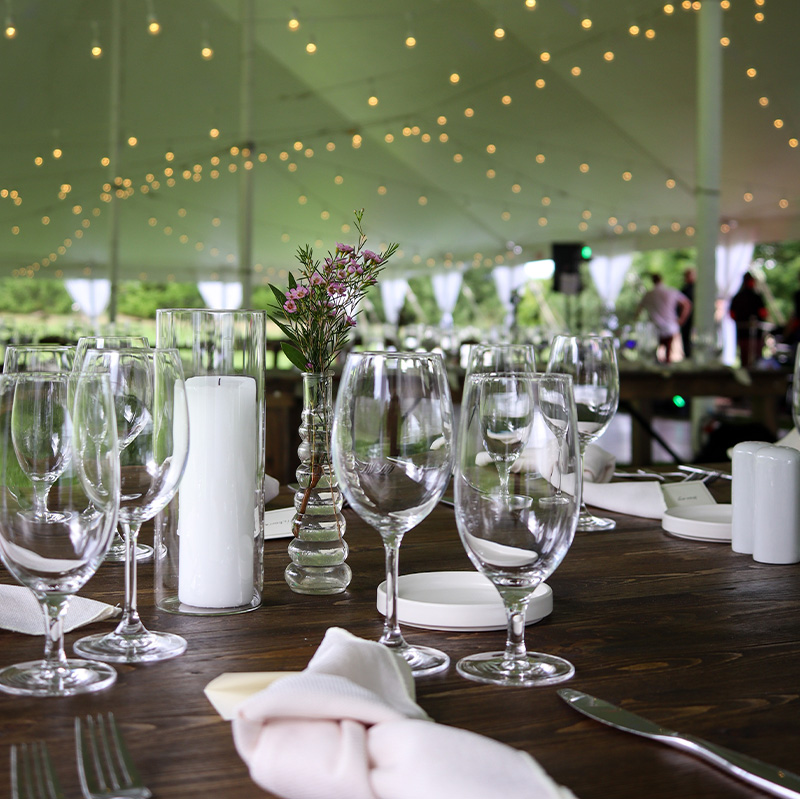 beautiful-table-setting-with-clear-glass-and-white-candles-for-a-corporate-event-tent-package