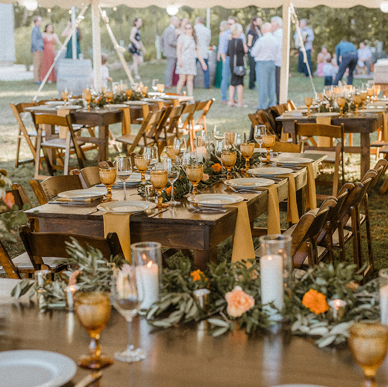 elegant-wedding-table-setting-with-guests-in-background-under-a-tent